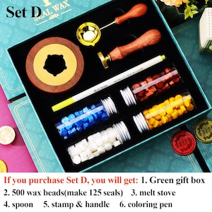 May include: A wax seal kit in a teal box, including a wooden handle stamp, a brass spoon, a melting stove, and a white pen. The kit also contains glass vials filled with colorful wax beads in red, yellow, blue, and white. The text "Set D" is visible.