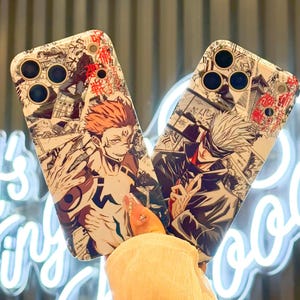 Op de afbeelding: Twee telefoonhoesjes met anime-illustraties. E&eacute;n hoesje toont een personage met rood haar, de andere een personage met wit haar. Beide hoesjes hebben een witte achtergrond met manga-panelen en rode accenten.