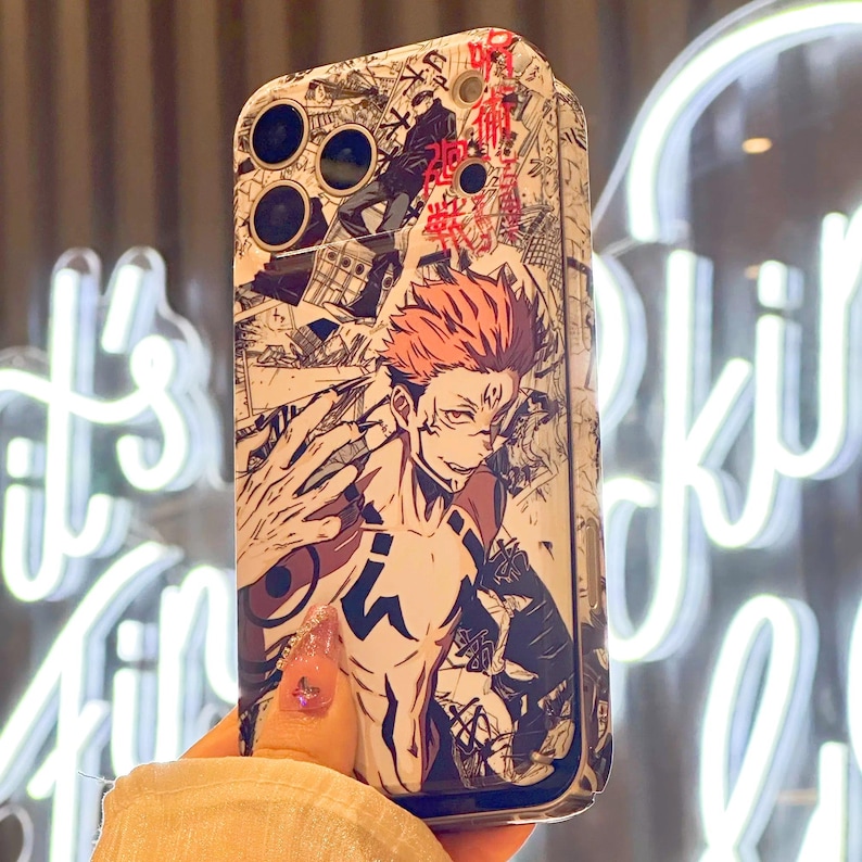 Op de afbeelding: Een telefoonhoesje met een manga-achtige illustratie van een personage met rood haar en tatoeages. De hoes heeft een zwart-wit stripboekontwerp met Japanse tekstaccenten. De hoes wordt in een hand gehouden.
