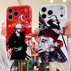 Op de afbeelding: Twee telefoonhoesjes met illustraties in anime-stijl. Eén hoesje is rood met een zwart-wit karakterontwerp en het woord "BLEACH". De andere hoes is wit met een zwart-oranje karakterontwerp.