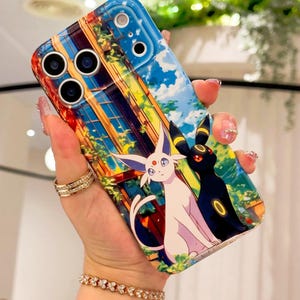 May include: A colourful phone case with an anime-style illustration. The design features a cityscape with blue skies and cartoon characters. The case is held by a hand with jewellery.