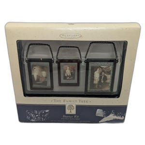 May include: A boxed set of three photo holder ornaments. Each ornament has a black frame and a hanging chain. The box has the text "Keepsake Ornament" and "The Family Tree Starter Kit Photo Holders".