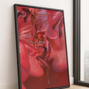 May include: Framed artwork featuring a close-up of two faces in a passionate embrace, rendered in shades of red and pink. The painting has a sensual theme, with a focus on lips and a single drop of liquid. The artwork is displayed in a black frame.