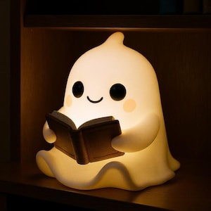 May include: A glowing white ghost-shaped night light reading a book. The light has a friendly face with black eyes and a smile, and it is holding a brown book. The light is sitting on a wooden shelf.