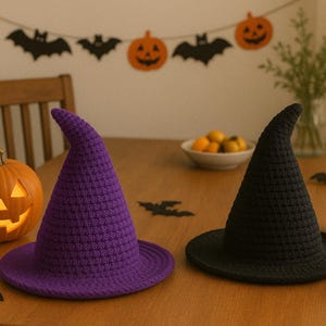 May include: A Halloween-themed still life featuring a purple and a black crochet witch hat. Decorative pumpkins and paper bats are scattered on a wooden table. A carved jack-o'-lantern and a festive banner complete the scene.
