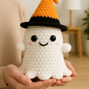 May include: A handmade white crochet ghost doll wearing a black and orange witch hat. The ghost has black eyes, rosy cheeks, and a smiling mouth. The doll has small, round arms and a scalloped bottom edge. A Halloween-themed decorative item.