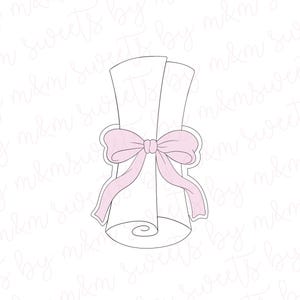 May include: A cookie cutter in the shape of a rolled-up scroll tied with a pink bow. The scroll is white, and the bow is a soft pink color. The design is simple and elegant, perfect for baking themed treats.