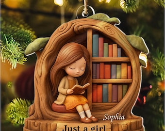 May include: A decorative ornament featuring a girl reading a book, seated in a tree-shaped structure with a bookshelf. The ornament has the text "Just a girl who loves Books" and the name "Sophia". The ornament is brown, with colorful books.
