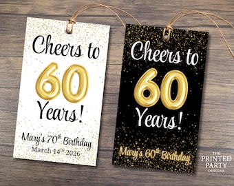 以下が含まれることがあります： 「Cheers to 60 Years!」の文字が黒い筆記体で書かれた2つの誕生日のギフトタグ。片方のタグは金色の紙吹雪が入った白、もう片方は金色の紙吹雪が入った黒です。タグには「Mary's 70th Birthday March 14th 2026」と「Mary's 60th Birthday」の文字も含まれています。