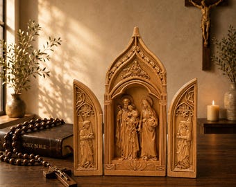 Può includere: Un trittico in legno raffigurante una scena religiosa, con figure scolpite all'interno di una cornice ad arco. Il pannello centrale mostra una famiglia, affiancata da pannelli laterali con figure di angeli. Un rosario e una Bibbia sono in primo piano.