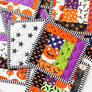 May include: Set of four Halloween-themed quilted pot holders. Each pot holder features a different patchwork design with orange, purple, black, green, and white fabrics. The designs include pumpkins, bats, spiders, and candy corn.
