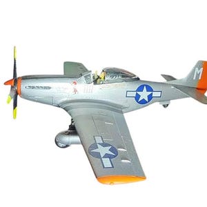 May include: A silver model airplane with orange and yellow accents. The plane features a blue star insignia on the wings and fuselage. The propeller is yellow and black. The tail has an orange tip with the letter "M".