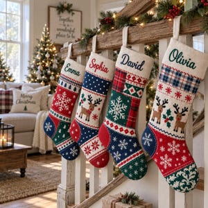 Pode incluir: Quatro meias de Natal personalizadas penduradas num corrim&atilde;o de madeira. Cada meia apresenta um design de patchwork &uacute;nico com padr&otilde;es festivos, incluindo flocos de neve, renas e xadrez, com os nomes Emma, Sophia, David e Olivia bordados.