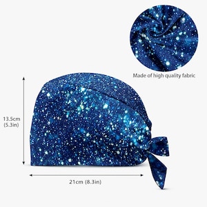 May include: A blue scrub cap featuring a white star and galaxy print. The cap measures 5.3 inches in height and 8.3 inches in width. A circular inset shows the fabric texture with the text Made of high quality fabric below the circle.