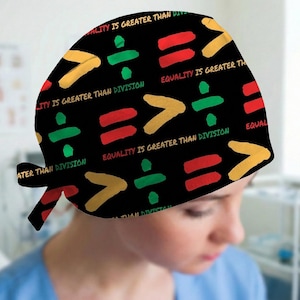 May include: A black scrub cap featuring a repeating pattern of mathematical symbols including division signs in green, equal signs in red, and greater-than signs in yellow, along with the repeated text "EQUALITY IS GREATER THAN DIVISION".
