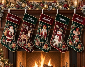 Pode incluir: Cinco meias de Natal de veludo em vermelho escuro e verde, cada uma com um nome bordado no topo: Madison, Nathan, Rachel, Victor e Amelia. As meias exibem cenas festivas bordadas do Pai Natal, uma rena, um quebra-nozes, um boneco de neve e um rato soldado.