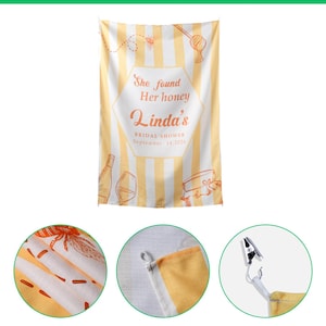 May include: A rectangular linen tapestry featuring vertical yellow and white stripes with orange illustrations of bees, a honey dipper, a wine bottle, a glass, and a jar. Text reads: She found Her honey Linda's BRIDAL SHOWER September 14, 2026.