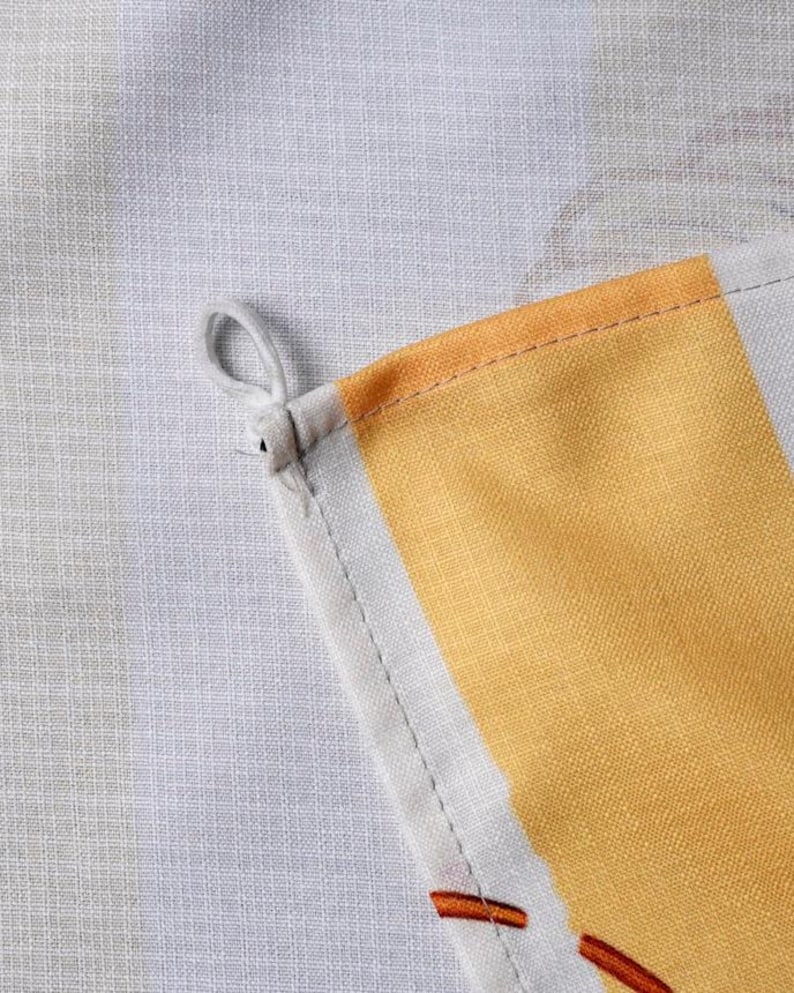 May include: A kitchen towel featuring a woven fabric texture with a light gray and white striped pattern. The towel includes a prominent yellow vertical stripe and a small white fabric loop attached to the corner for hanging purposes.