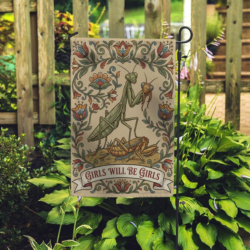 May include: A garden flag featuring a detailed illustration of two praying mantises and a grasshopper, set against a beige background with floral accents. The flag includes the text "GIRLS WILL BE GIRLS" on a banner.