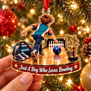 May include: A clear acrylic Christmas ornament featuring a bowling scene with a person throwing a ball down a lane, a bowling bag labeled MASON, a trophy, and the text Just A Boy Who Loves Bowling printed on a red base with gold stars.