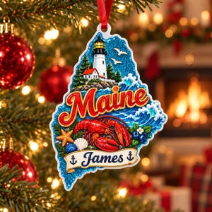 May include: A Maine-shaped Christmas ornament featuring a lighthouse, a red lobster, a starfish, seashells, and blueberries. The word Maine is written in large red letters, and a banner at the bottom displays the name James with anchor icons.