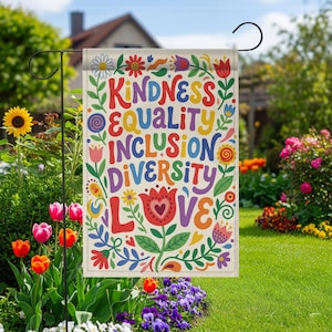 May include: A garden flag with the words "KINDNESS, EQUALITY, INCLUSION, DIVERSITY, LOVE" in colorful, whimsical lettering. The flag is decorated with floral and leaf designs in a garden setting.