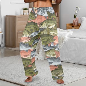 May include: Pajama pants with a repeating pattern of various fish in shades of green, gray, and salmon. The fish are arranged in a stacked, overlapping design. The pants are made of a soft, lightweight fabric.