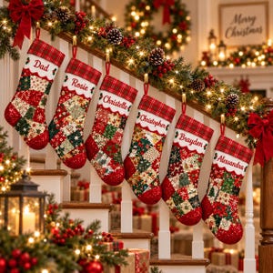 May include: Six Christmas stockings hanging on a white staircase railing. Each stocking features a patchwork pattern of red, green, and cream fabric with festive motifs, a red plaid cuff, and a white embroidered name: Dad, Rosie, Christelle, Christopher, Brayden, and Alessandra.