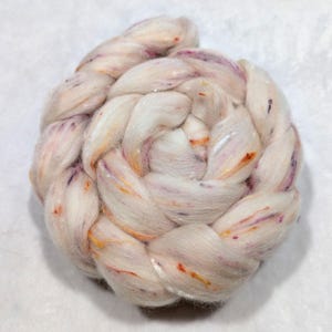 May include: A white, fluffy yarn with orange, pink, and purple flecks. The yarn is braided and twisted into a ball shape.