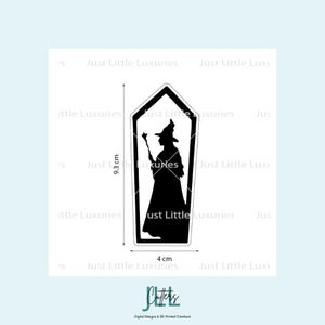 May include: A black witch silhouette inside a black-framed, coffin-shaped design. The witch is holding a wand. The design is 9.3 cm tall and 4 cm wide. The text "Just Little Luxuries" is repeated around the design.