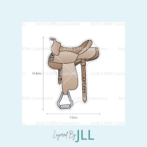 May include: A light brown saddle cookie cutter. The cutter is 4.1 inches tall and 3 inches wide. The text "Layered By JLL" is at the bottom of the image.