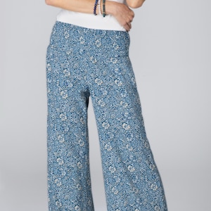 Peut inclure: Pantalon large à motif floral bleu. Le pantalon présente un fond bleu clair avec un motif floral blanc répété. Il est fabriqué dans un tissu léger et a une coupe décontractée.
