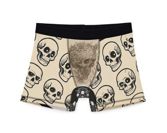 May include: Boxer briefs with a beige background and a repeating pattern of black and white skulls. The center panel features a detailed sepia-toned skull design. The waistband is black.