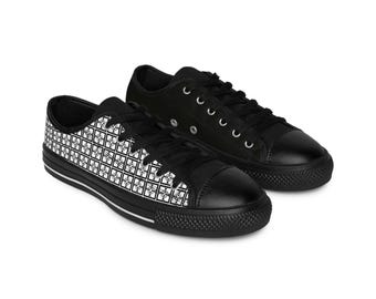 May include: Black canvas sneakers. One shoe features a white geometric pattern, while the other is solid black. Both have black laces, rubber soles, and toe caps. A stylish and versatile footwear option.