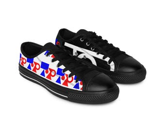 May include: Black canvas sneakers with white soles and black laces. One shoe features a pattern of red and blue shapes on a white background. The other shoe has a white design on a black background.
