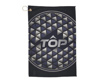 May include: A black golf towel with a geometric pattern of silver and navy blue triangles. The word "TOP" is printed in white at the center. A gold-colored metal grommet is at the top for hanging.