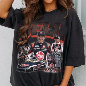 May include: Dark gray t-shirt featuring a collage of a race car and a driver in a racing suit. The shirt includes the word "RHEEM" and the driver's name "Christopher". The shirt has a vintage, distressed look.