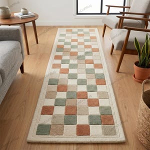 May include: A rectangular runner rug featuring a repeating checkered pattern of squares in muted sage green, terracotta orange, and cream. The rug has a thick, textured pile and a solid cream-colored border framing the entire geometric design.