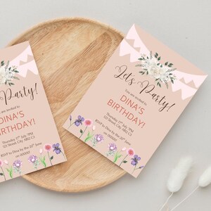 May include: Two pink birthday party invitations with floral and decorative elements. The invitations read "Let's Party!" and "Dina's Birthday!" with event details. The invitations are on a wooden tray.
