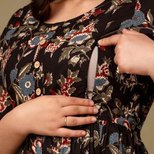 May include: Black floral print dress with a button-down front and a scoop neckline. The dress features a nursing-friendly design with a hidden opening. The floral pattern includes red, blue, and white flowers on a black background.