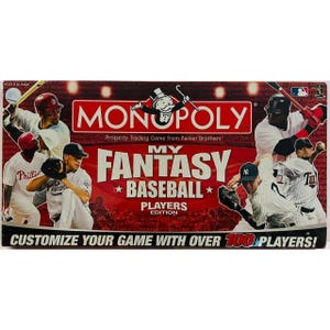 May include: A Monopoly My Fantasy Baseball Players Edition game box. The box is red with white text and features baseball players in action. The text reads "Customize your game with over 100 players!"