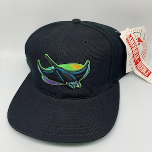 Op de afbeelding: Zwarte baseballcap met een platte klep. De pet heeft een geborduurd ontwerp van een manta rog in blauw, groen, paars en geel. Het label luidt "AMERICAN NEEDLE QUALITY HEADWEAR SINCE 1918".