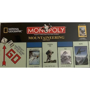 May include: Monopoly Mountaineering Edition board game. The game box features the National Geographic and Monopoly logos, with images of mountains and climbers. The game includes custom pewter tokens and is for ages 8 to adult.
