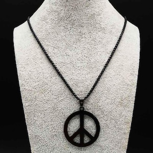 May include: A black peace symbol pendant necklace. The pendant features a circular design with a vertical line and three diagonal lines. The chain is also black and made of small, linked segments. The necklace is displayed on a white mannequin.
