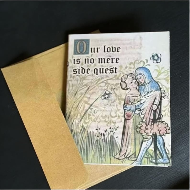 May include: A greeting card with an illustration of a medieval couple embracing, with the text "Our love is no mere side quest." The card is inside a brown envelope, with a black background.