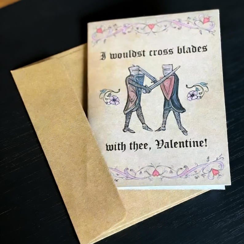 May include: A Valentine's Day card with a medieval theme. The card features two knights crossing swords, with the text "I wouldst cross blades with thee, Valentine!" The card is in a brown envelope.