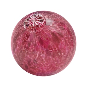 Peut inclure: Une boule en verre rose avec un dessus en verre transparent et un motif décoratif. La boule a un aspect marbré et moucheté.