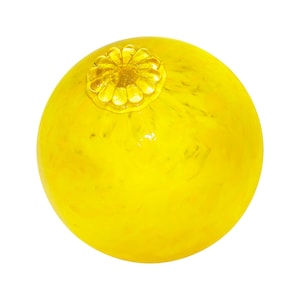May include: A bright yellow glass ball with a decorative flower design on the top.