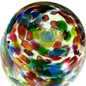 May include: A clear glass vase with a colorful confetti pattern. The bottom of the vase is signed "Charmaine Jones 2019".