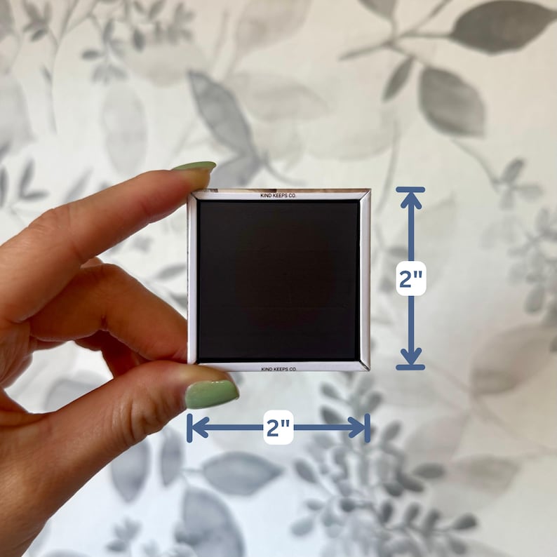 K&ouml;nnte beinhalten: Ein quadratischer schwarzer Magnet mit wei&szlig;em Rand und dem Text KIND KEEPS CO. auf der oberen und unteren Kante. Der Magnet misst 5,08 cm mal 5,08 cm, wie durch die blauen Ma&szlig;pfeile im Bild deutlich erkennbar ist.